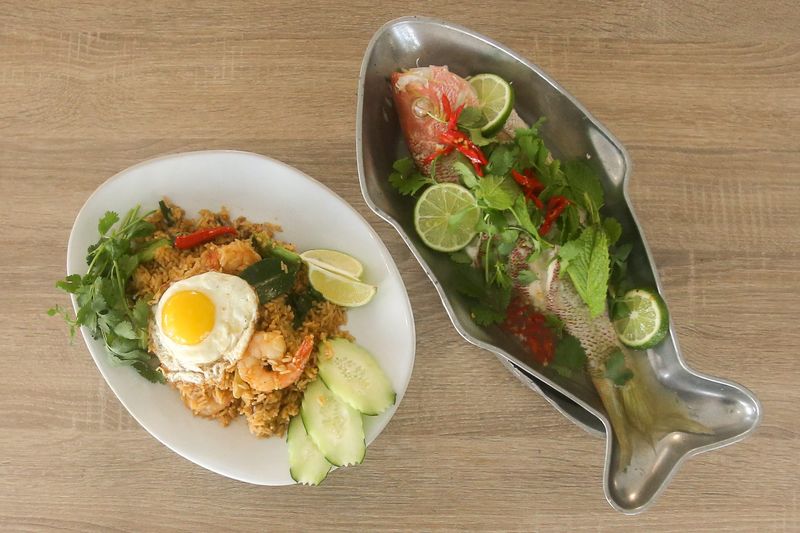 Plates of Tom Yum Fried Rice and Pla Neung Manao rest on a table at BKK thai kitchen + bar in Corpus Christi, Texas, on Thursday, Dec. 26, 2024. The two dishes will be added to the restaurant's menu in January 2025.