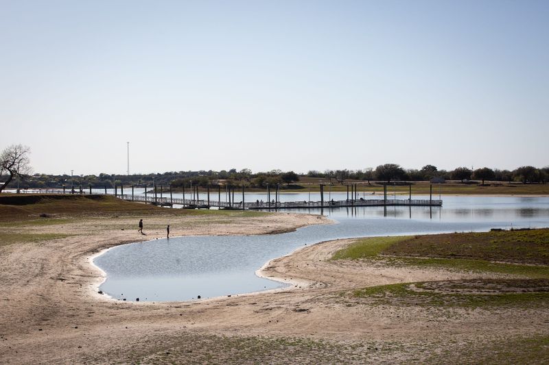People fish from a pier and explore the receding shoreline of Lake Corpus Christi at the state park in Mathis on March 11.