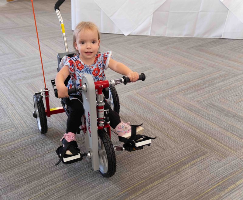 Penelope Klein, 2, smiles as she rides her new AMTryke, provided by AMBUCS of Amarillo. The adaptive trike will allow her to participate in family activities despite challenges from spina bifida
