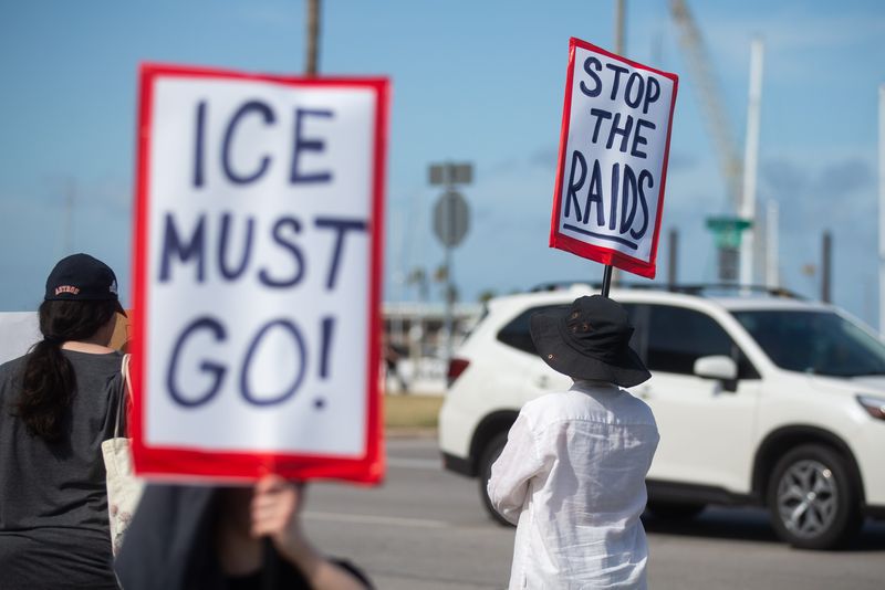 Protesters against immigration raids hold signs at a community demonstration in downtown Corpus Christi on June 10, 2025.