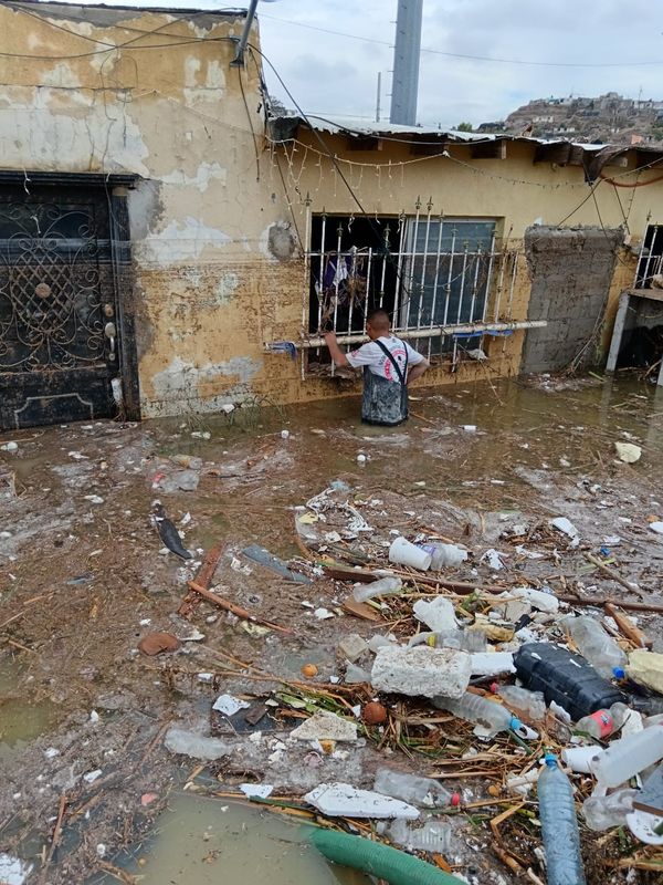 A Juárez man wades through debris-filled, waist-deep water following a flash flood that damaged hundreds of homes in Juárez, Mexico, on June 25, 2025.