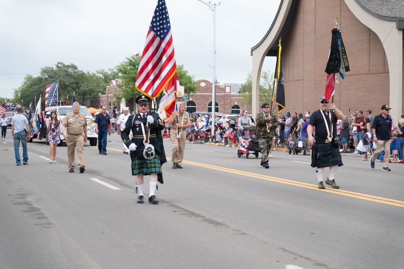 Veterans and color guard members march with flags down Fourth Avenue during Canyon’s Fourth of July Parade, honoring military service and American freedom.