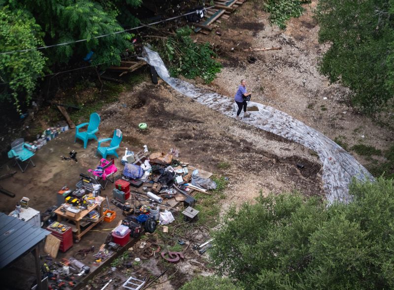 A woman is seen moving belongings from a home damaged by flooding from Big Sandy Creek from Star Flight near Lago Vista, Sunday, July 6, 2025.