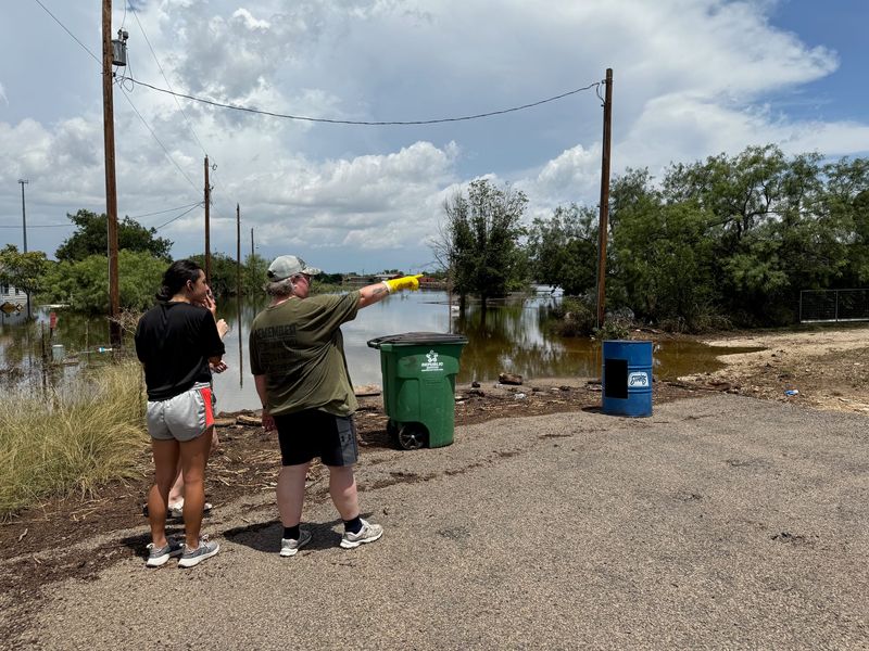 Laura Debusk of New Mexico exchanges information and talks with a neighbor's family Sunday in San Angelo, Texas. Her sister Keri Patton's home was inundated in the Fourth of July flood.