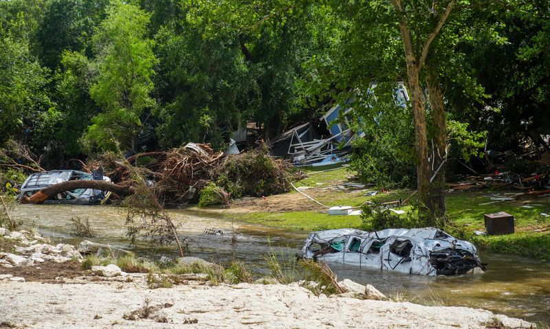 Destroyed vehicles sit in floodwaters as volunteers clean up and recover belongings on July 7, 2025, following a weekend flash flood that devastated homes in Leander, Texas.