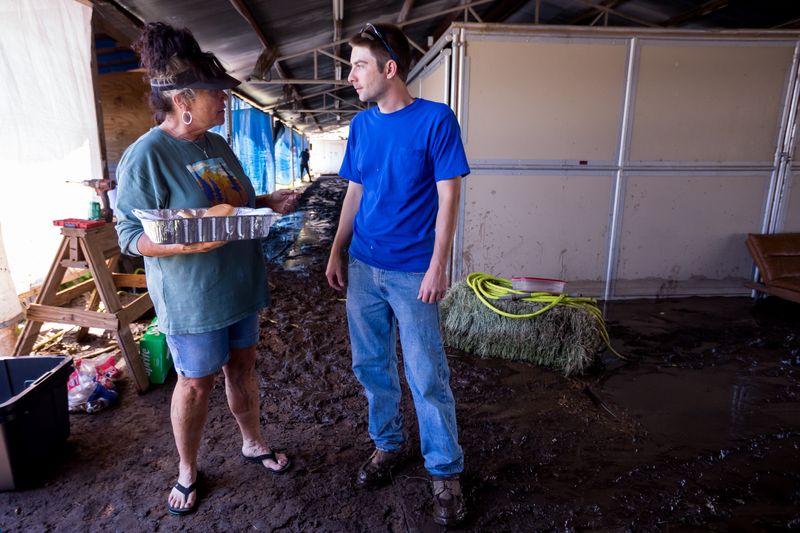 Horse owner Tia Mills brings burgers to workers cleaning the stables at Ruidoso Downs Racetrack on July 9, 2025, after historic flooding the day before in Ruidoso, New Mexico.