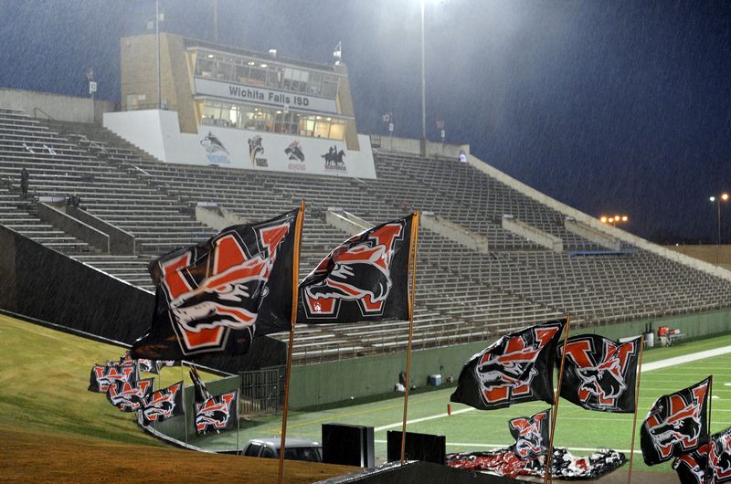 Rain-drenched flags from Wichita Falls High School line the edge of the ramp to the locker rooms as rain pours down at Memorial Stadium in 2014. Heavy thunderstorms postponed the Coyotes' matcup against Azle.