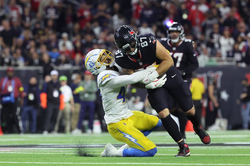 Jan 11, 2025; Houston, Texas, USA; Los Angeles Chargers linebacker Troy Dye (43) tackles Houston Texans tight end Cade Stover (87) during the third quarter in an AFC wild card game at NRG Stadium. Mandatory Credit: Troy Taormina-Imagn Images