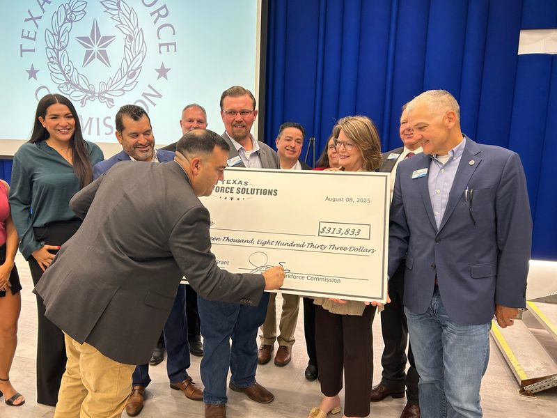 Texas Workforce Commissioner Joe Esparza signs a check awarding Del Mar College a grant on Aug. 8.