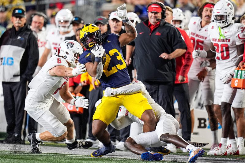 Michigan running back Jordan Marshall (23) runs against New Mexico defensive lineman Jaxton Eck (6) and cornerback Abraham Williams (2) during the second half at Michigan Stadium in Ann Arbor on Saturday, August 30, 2025.