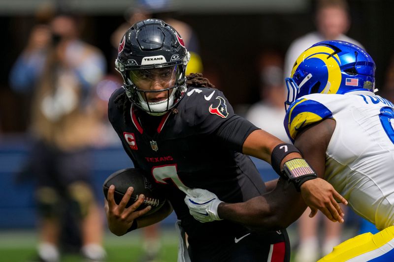 Sep 7, 2025; Inglewood, California, USA; Houston Texans quarterback C.J. Stroud (7) tries to escape the tackle of Los Angeles Rams linebacker Byron Young (0) at SoFi Stadium. Mandatory Credit: Kirby Lee-Imagn Images