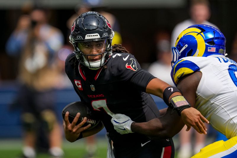 Sep 7, 2025; Inglewood, California, USA; Houston Texans quarterback C.J. Stroud (7) tries to escape the tackle of Los Angeles Rams linebacker Byron Young (0) at SoFi Stadium. Mandatory Credit: Kirby Lee-Imagn Images