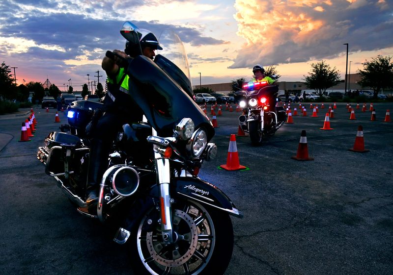 Abilene Police Department motorcycle officers Loren Adlesperger (foreground) and Greg Young demonstrate their riding skills on a course in front of APD headquarters Tuesday. The annual National Night Out featured public safety representatives from APD, DPS and others, as well as vehicles and equipment for kids to explore.