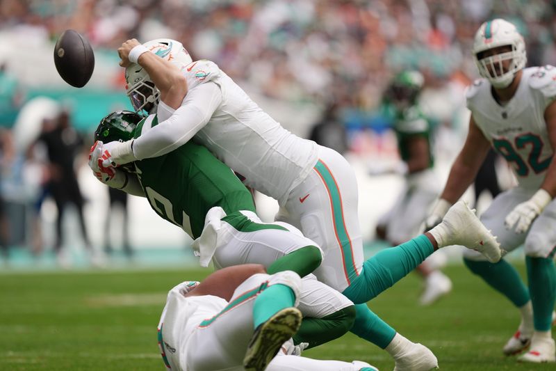 Miami Dolphins linebacker Bradley Chubb, top, and defensive tackle Christian Wilkins, bottom, hit New York Jets quarterback Zach Wilson (2) causing a fumble during the first half of an NFL game at Hard Rock Stadium in Miami Gardens, Dec. 17, 2023.