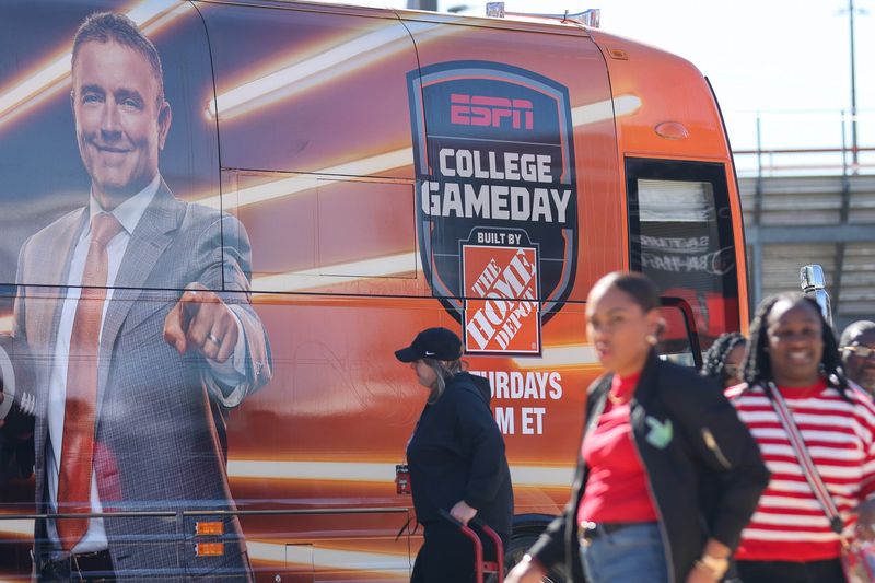 Red Raider fans walk in front of an ESPN College GameDay bus on the Texas Tech University campus on Nov. 7, 2025 in Lubbock, Texas. The program will broadcast live on Saturday morning leading into the Red Raiders v. BYU Cougars football game.