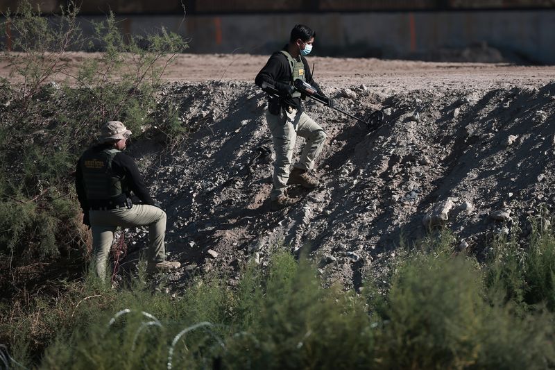 A U.S. Border Patrol Agents comb an area near the border with a metal detector. The location is where Spanish-language journalists on both sides of the border report that a Border Patrol vehicle came under gunfire.