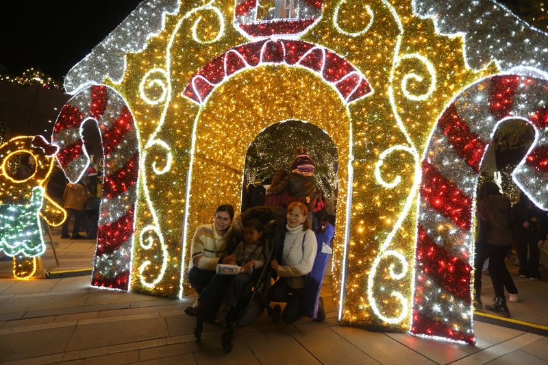 Attendees pose for photos with decorations during the WinterFest tree-lighting at San Jacinto Plaza, Saturday, Nov. 22, 2025, in El Paso, Texas.