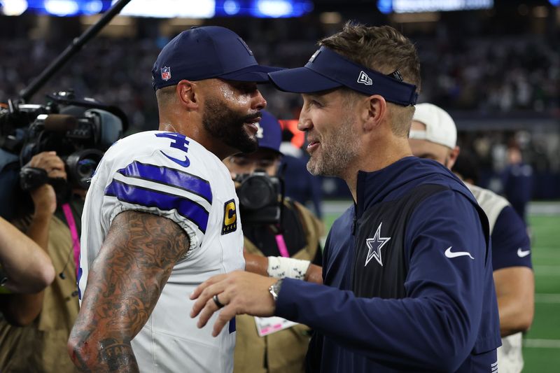 ARLINGTON, TEXAS - NOVEMBER 23: Dak Prescott #4 and Brian Schottenheimer of the Dallas Cowboys hug after the game against the Philadelphia Eagles in the game at AT&T Stadium on November 23, 2025 in Arlington, Texas. The Cowboys won 24-21. (Photo by Stacy Revere/Getty Images)