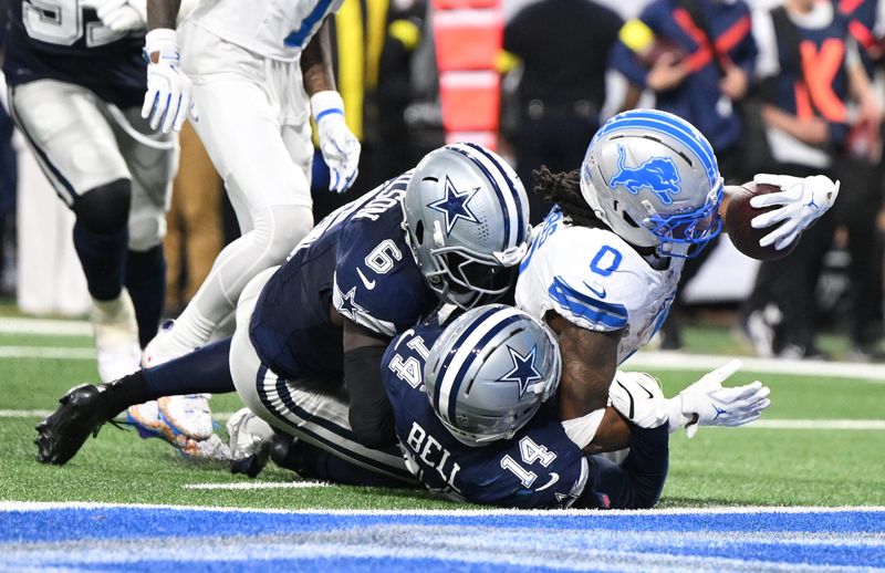 Dec 4, 2025; Detroit, Michigan, USA; Detroit Lions running back Jahmyr Gibbs (0) scores a touchdown against Dallas Cowboys safety Markquese Bell (14) and safety Donovan Wilson (6) during the second half at Ford Field. Mandatory Credit: Lon Horwedel-Imagn Images
