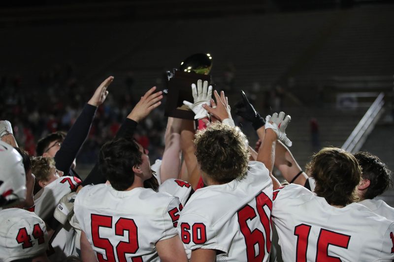 Members of the Muenster Hornets host the trophy after the game against the Gruver Greyhounds in the Class 2A Division II state semifinal game Thursday, Dec. 11, 2025, at Happy State Bank Stadium in Canyon.