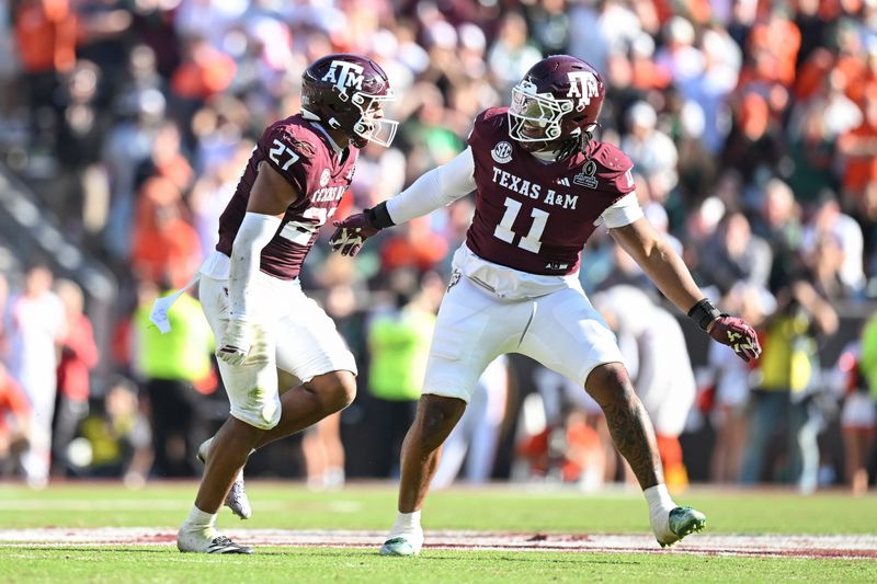 Dec 20, 2025; College Station, TX, USA; Texas A&M Aggies linebacker Daymion Sanford (27) reacts with defensive tackle Tyler Onyedim (11) after recovering a fumble against the Miami Hurricanes during the second half of the first round game of the CFP National Playoff at Kyle Field. Mandatory Credit: Maria Lysaker-Imagn Images
