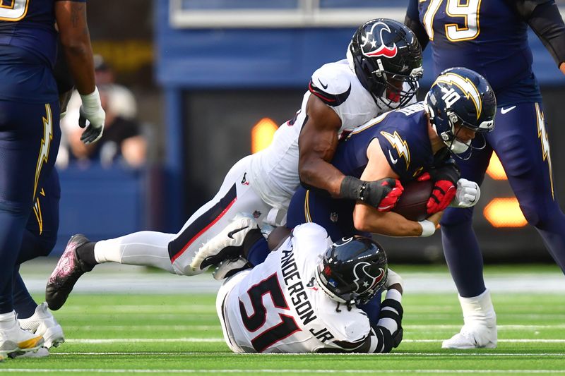 Dec 27, 2025; Inglewood, California, USA; Los Angeles Chargers quarterback Justin Herbert (10) is sacked by Houston Texans defensive end Danielle Hunter (55) and defensive end Will Anderson Jr. (51) during the first half at SoFi Stadium. Mandatory Credit: Gary A. Vasquez-Imagn Images