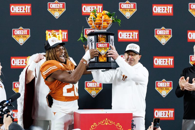 Dec 31, 2025; Orlando, FL, USA; Texas Longhorns linebacker Ty'Anthony Smith (26) and head coach Steve Sarkisian raise the Cheez-It Citrus Bowl trophy after a game against the Michigan Wolverines at Camping World Stadium. Mandatory Credit: Matt Pendleton-Imagn Images