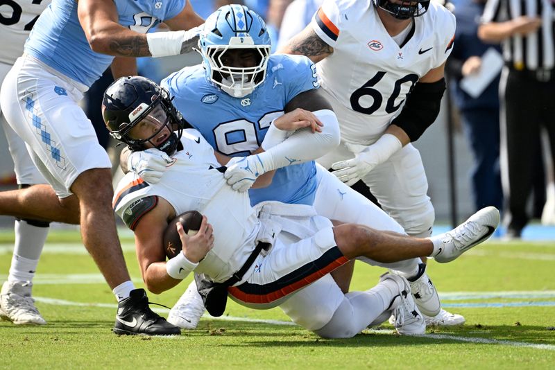 Oct 25, 2025; Chapel Hill, North Carolina, USA; Virginia Cavaliers quarterback Chandler Morris (4) is sacked by North Carolina Tar Heels defensive lineman CJ Mims (92) in the first quarter at Kenan Stadium. Mandatory Credit: Bob Donnan-Imagn Images