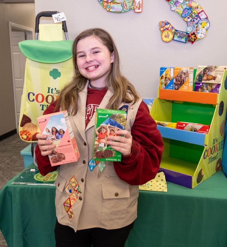 Mackenzie McManus, 11, shows boxes of Thin Mints and Exploremores in front of a cookie display highlighting the return of Girl Scout cookie season.