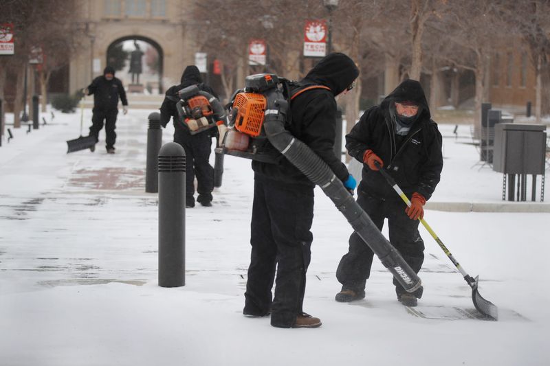 Texas Tech Grounds Operations employees used show shovels and leaf blowers to clear the snow and ice off of the ice-covered walkway between the Administration Building and the Student Union building. Lubbock experienced temperatures below 10 degrees Saturday morning, Jan. 24, 2026 in Lubbock.