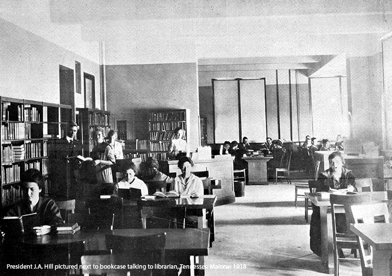 President J.A. Hill pictured next to bookcase talking to librarian, Tennessee Malone: 1918.