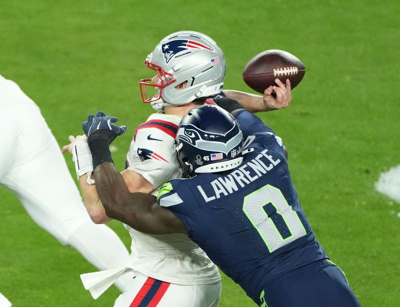 Feb 8, 2026; Santa Clara, CA, USA; New England Patriots quarterback Drake Maye (10) is hit as he throws by Seattle Seahawks defensive end DeMarcus Lawrence (0) in the second half in Super Bowl LX at Levi's Stadium. Mandatory Credit: Kirby Lee-Imagn Images