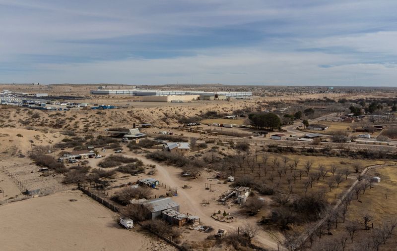 Homes in an agricultural area of Clint and Socorro are seen on Feb. 12, 2026. In the distance, warehouses—purchased by the Department of Homeland Security for about $123 million and planned to house up to 8,500 people as a migrant detention center—rise on the outskirts of Socorro, Texas.