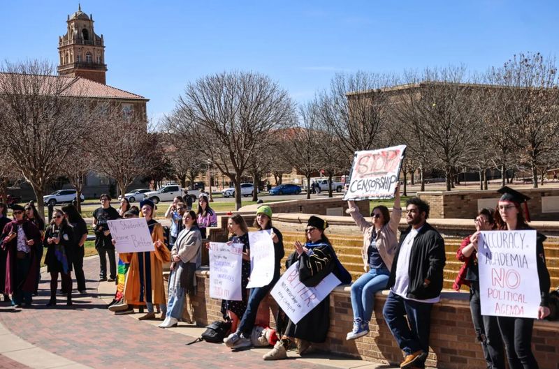 Texas Tech students and faculty stand with signs and chant at a rally protesting recent curriculum changes from Tech System Chancellor Brandon Creighton at Memorial Circle on campus in Lubbock on Feb. 26, 2026.