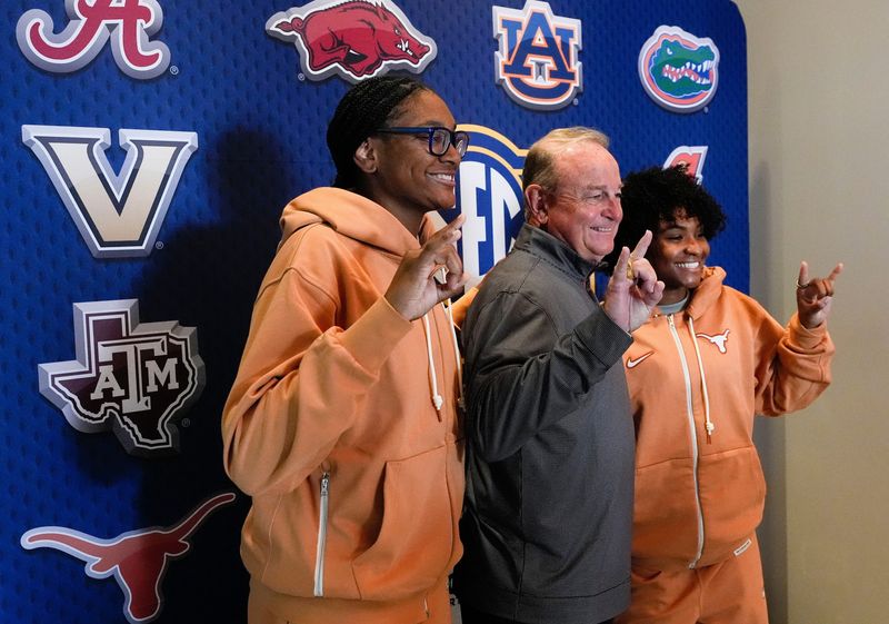 Texas players Madison Booker and Rori Harmon give the Hook â€˜em Horns sign with head coach Vic Schaefer as they arrive for SEC Media Day at the Grand Bohemian Hotel in Mountain Brook Tuesday, Oct. 16, 2024.