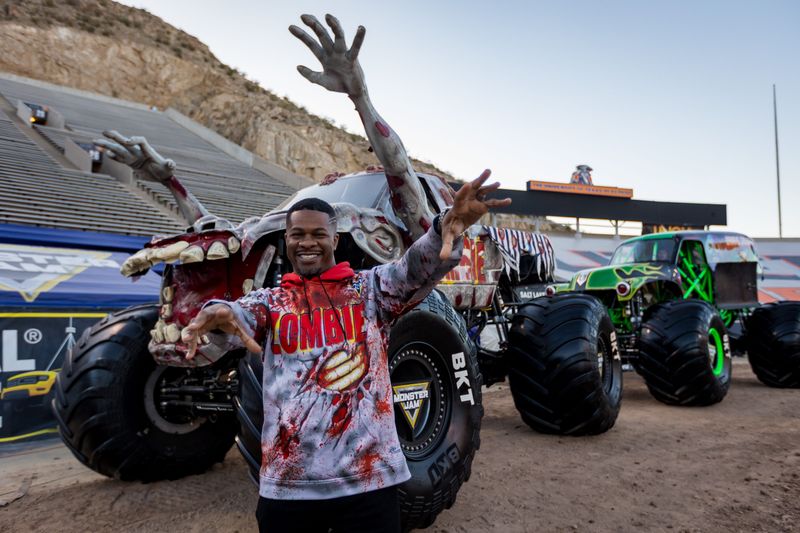 Zombie driver Bari Musawwir stands next to the Zombie monster truck Friday, March 13, 2026, at Sun Bowl Stadium with the Grave Digger monster truck behind him ahead of Monster Jam in El Paso on Saturday and Sunday.