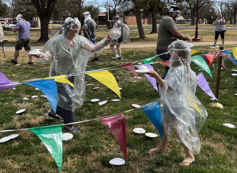 Plates fly as protected partipicants enjoy the pie fight at the end of the Pi Day celebration, Saturday, March 14 on the East Lawn of the Pahandle-Plains Historical Museum in Canyon.