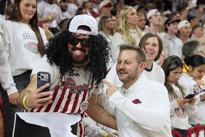 Jan 31, 2026; Fayetteville, Arkansas, USA; Arkansas Razorbacks head coach coach Ryan Silverfield takes a photo with a fan during a timeout in the first half against the Kentucky Wildcats at Bud Walton Arena. Mandatory Credit: Nelson Chenault-Imagn Images