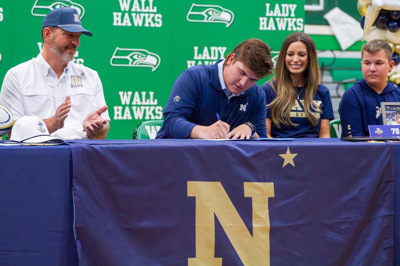 Baine Jenschke (middle) signs an academic scholarship to play Rugby at the U.S. Naval Academy at Wall High School on Tuesday, April 7, 2026.