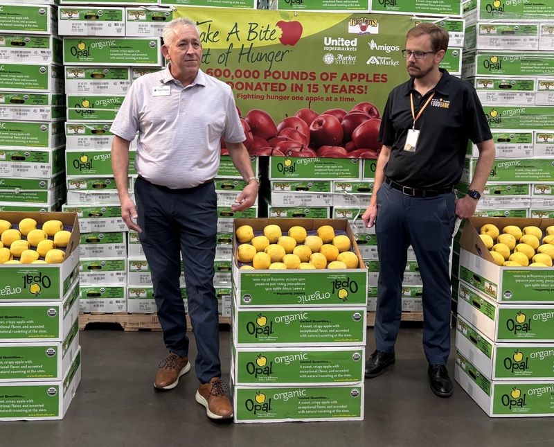 Travis Chaney with The United Family stands with Zack Wilson and more than 6,000 pounds of organic apples, which will be distributed through 29 counties in the next week.