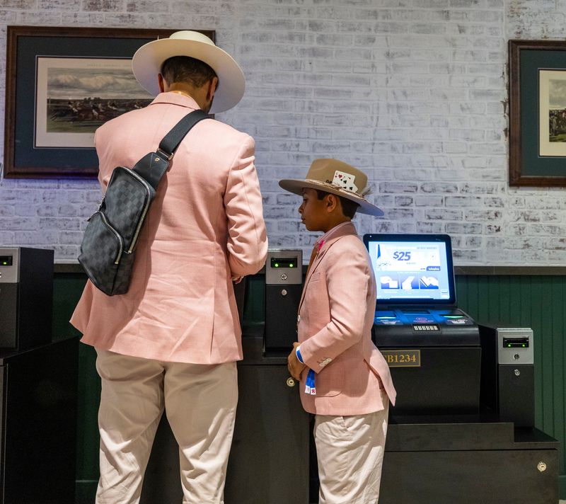 Father Nemish Patel and son Devin wear matching suits while placing a bet at Churchill Downs on Oaks, one day before 2026 Kentucky Derby. May 1, 2026