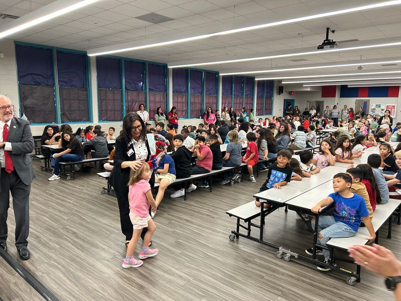 Menger Elementary School Principal Christina Barrera greets a student who reached out for a hug after Barrera was surprised with an award recognition on May 5.