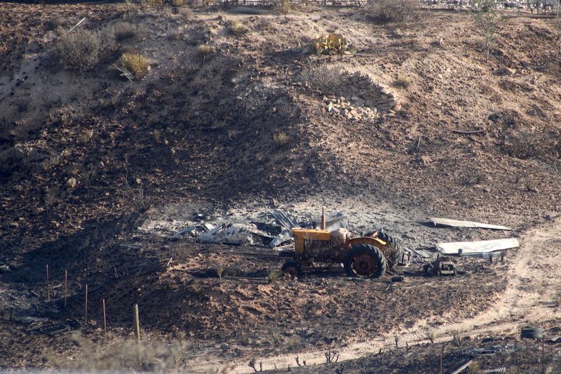 Farm equipment sits next to a burnt struture from the Stinky Fire, which started at the city landfill northwest of Amarillo May 17 and quickly spread into nearby neighborhoods after breaching a containment line May 18.