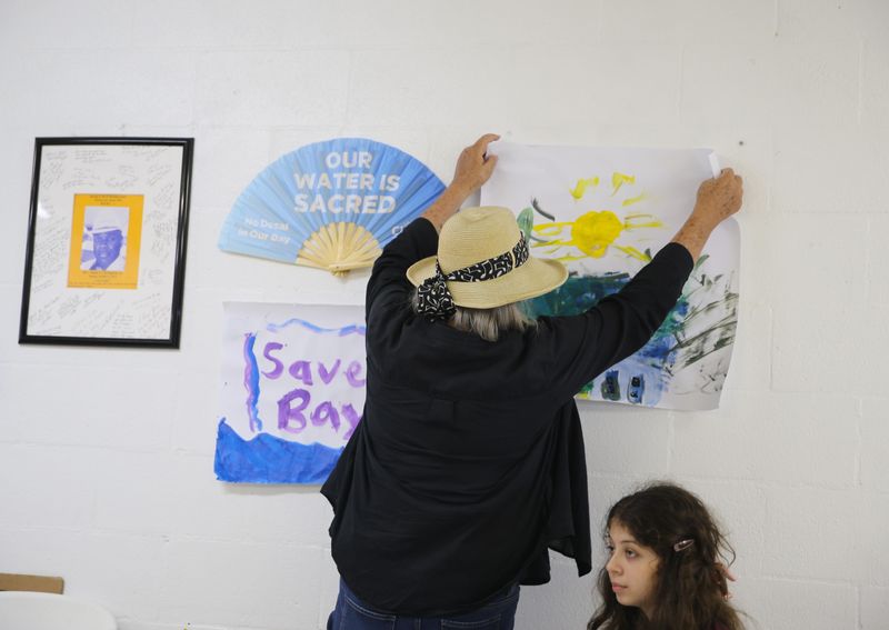 Pamela Meyer affixes a painting to a wall featuring images supporting the environment and the Hillcrest neighborhood at Brooks AME Worship Center in Corpus Christi on May 29, 2026.