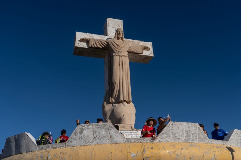 Hikers arrive near the top of Mount Cristo Rey on May 30, 2026, near Sunland Park, N.M., with the international border visible at left.