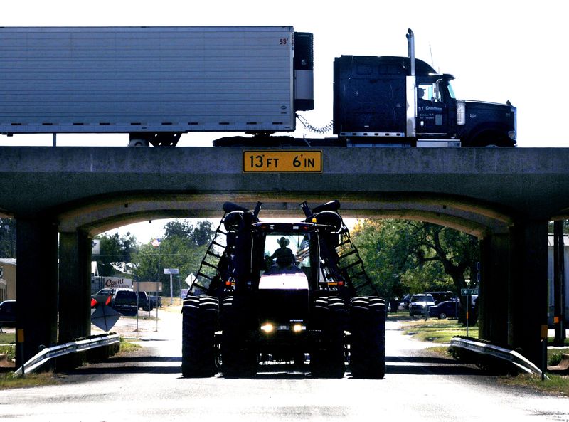 A farm tractor drives under the Interstate 20 overpass at FM 126 in Merkel while a west-bound semi-truck passes by overhead in 2006. The Texas Dept. of Public Safety is now requiring commercial learner's permit knowledge exam applicants to conduct those tests only in English.
