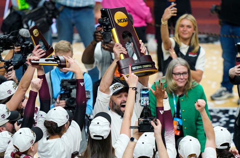 Dec 21, 2025; Kansas City, MO, USA; Texas A&M Aggies head coach Jamie Morrison hoists the 2025 NCAA Women’s Volleyball Championship trophy after defeating the Kentucky Wildcats at T-Mobile Center. Mandatory Credit: Jay Biggerstaff-Imagn Images