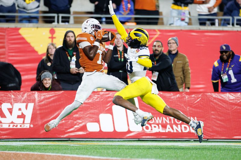 Dec 31, 2025; Orlando, FL, USA; Texas Longhorns wide receiver Kaliq Lockett (7) makes a catch for a touchdown over Michigan Wolverines defensive back Jyaire Hill (20) during the second half at Camping World Stadium. Mandatory Credit: Matt Pendleton-Imagn Images