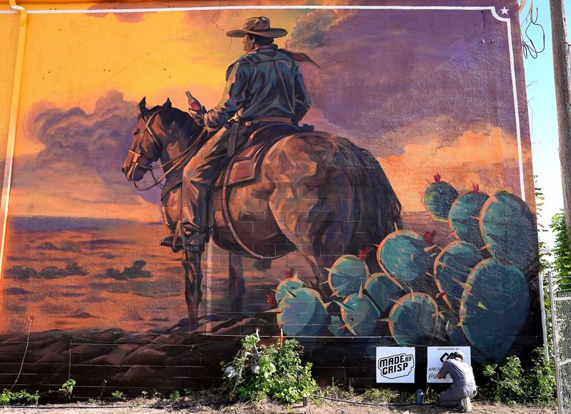 Muralist Caleb Crisp smooths the stencils he is using to autograph his work July 2. Over 100 feet wide, the mural at 113 Cherry Street faces Abilene’s South First Street and Treadway Boulevard intersection. Abilene was one of three Texas towns to receive a mural in this project between Coca-Cola Southwest Beverages and Texas Monthly.