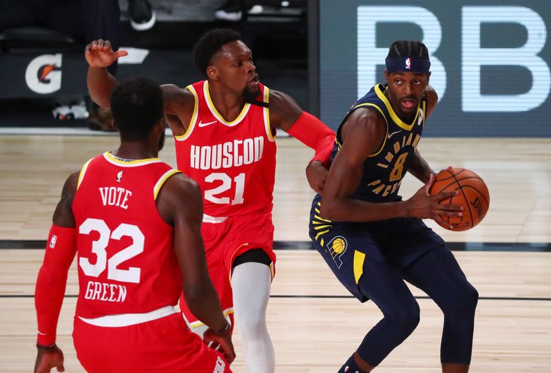 Aug 12, 2020; Lake Buena Vista, Florida, USA; Indiana Pacers forward Justin Holiday (8) drives to the basket against Houston Rockets guard Michael Frazier (21) and forward Jeff Green (32) in the fourth quarter of a NBA basketball game at AdventHealth Arena. Mandatory Credit: Kim Klement-USA TODAY Sports